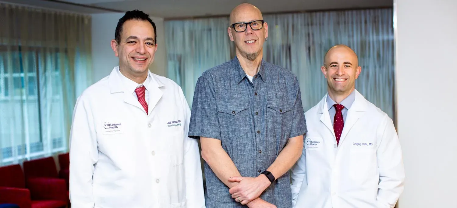 A patient stands with cardiologists Dr. Louai Razzouk and Dr. Gregory Katz.
