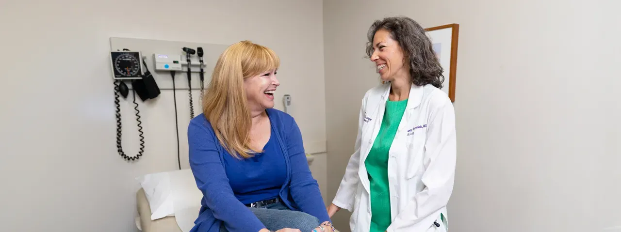 Dr. Harmony R. Reynolds talks to a woman sitting on an exam table.